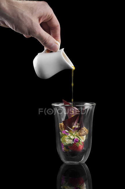 Hand gießt Sauce auf Dessert im Glas — Stockfoto
