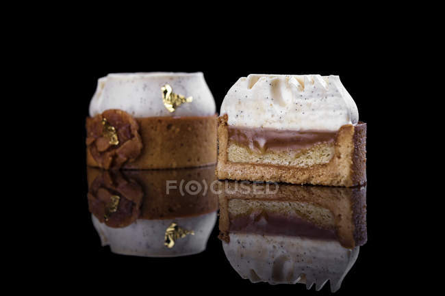 Gâteaux ronds avec décoration crème sur fond noir — Photo de stock