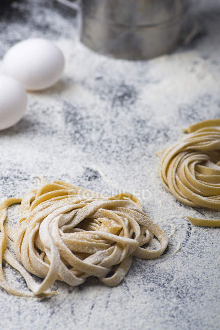 Homemade pasta on kitchen table with eggs — Stock Photo