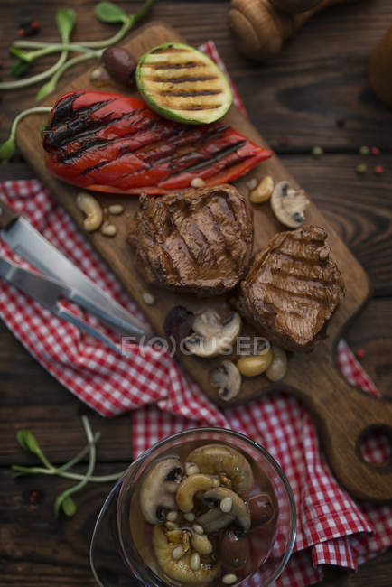 Vista superior de bifes de carne com legumes grelhados e cogumelos — Fotografia de Stock