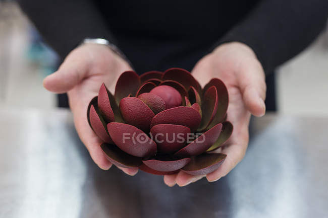 Primer plano de las manos femeninas con decoración de flores de chocolate - foto de stock