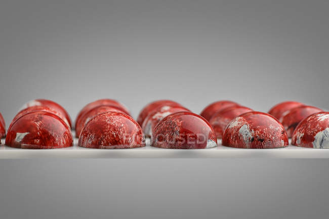 Chocolate candies with red marble glaze — Stock Photo