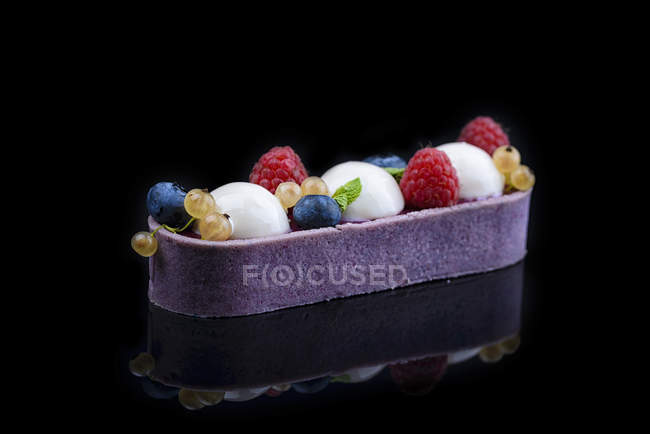 Kuchen mit Sahne und frischen Beeren auf schwarzem Hintergrund — Stockfoto