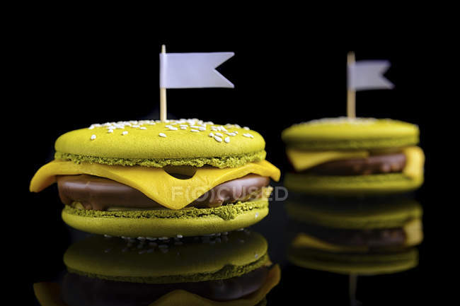 Macarons shaped as cheeseburgers on black background — Stock Photo