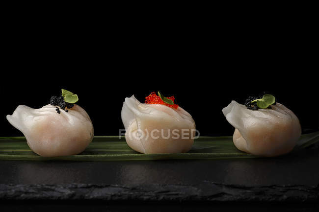 Dumplings decorated with caviar served on leaf — Stock Photo