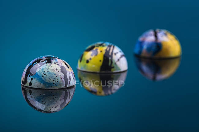 Colorful marble glaze candies on blue mirror surface — Stock Photo