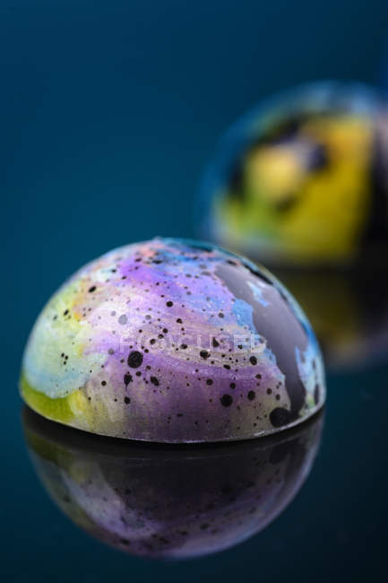 Фіолетові мармурові глянцеві цукерки на дзеркальній поверхні — стокове фото