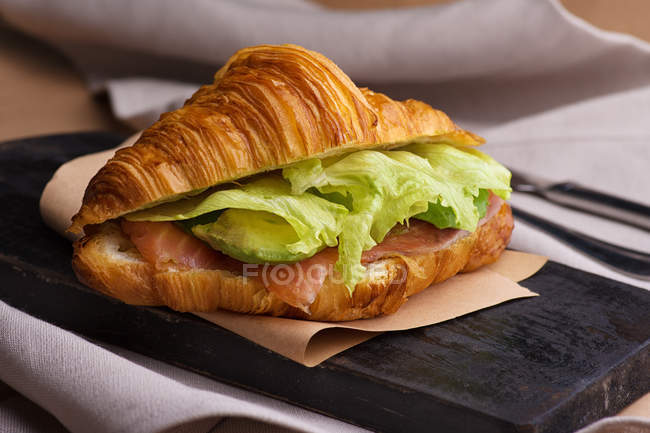 Close-up of croissant with avocado and sliced salmon served on plate — Stock Photo