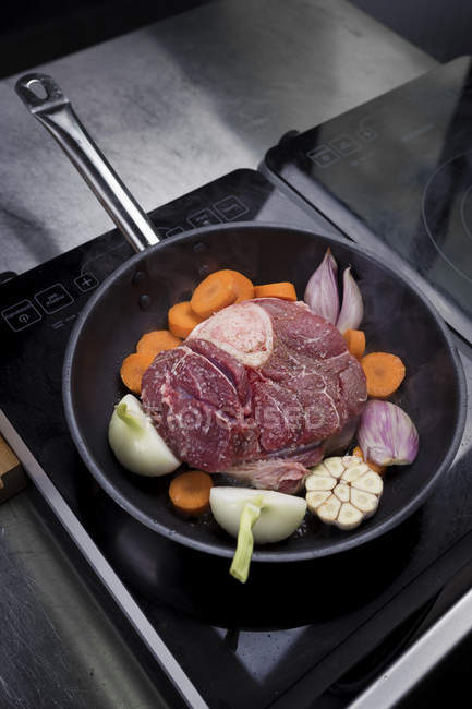 Приготовление говядины и овощей в сковороде на плите — стоковое фото