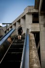 Visão traseira da mulher levantando na escada rolante de rua em Miami, EUA — Fotografia de Stock