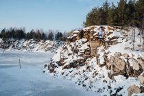 Snow-covered rocky cliffs at frozen lake shore — Stock Photo