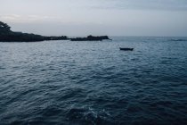 Paysage marin de falaises côtières et bateau flottant vide au crépuscule — Photo de stock
