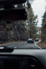 Vista através de vidro de vento para carros andando na estrada da montanha — Fotografia de Stock