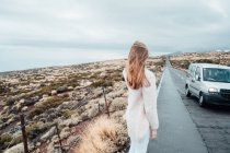 Visão traseira da menina loira na beira da estrada costeira — Fotografia de Stock