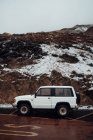 Side view of off-road car parked at roadside on background of snow-covered cliffs — Stock Photo