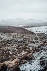 Трав'яна долина вкрита снігом, гірський хребет на фоні — стокове фото