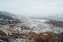 Трав'яна долина вкрита снігом, гірський хребет на фоні — стокове фото
