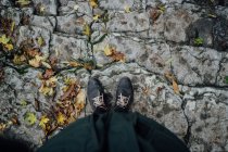 Женские ноги стоят на каменистой лестнице с осенними листьями — стоковое фото