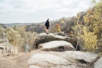 Distant view of backpacker standing on boulder at countryside — Stock Photo