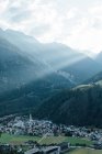 Ідилічний вид на сонячні промені над гірською долиною з невеликим містом — стокове фото