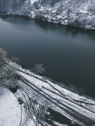 Vue en angle élevé sur la rive de la rivière d'hiver avec des pistes de roue — Photo de stock