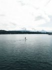 Vista a distanza della persona che galleggia a bordo al fiume — Foto stock