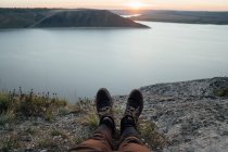 Ноги туриста, отдыхающего на берегу широкой реки — стоковое фото