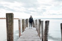 Blonde woman posing at wooden pier at frozen lake — Stock Photo