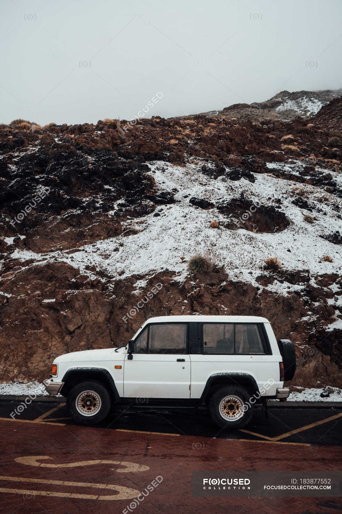 Side view of off-road car parked at roadside on background of snow-covered  cliffs — wheels, asphalt - Stock Photo | #183877552