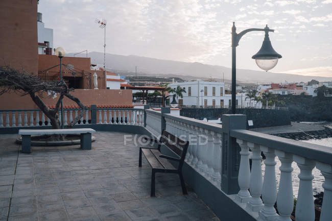 Скамейки на балконе над вечерним городским пейзажем — стоковое фото