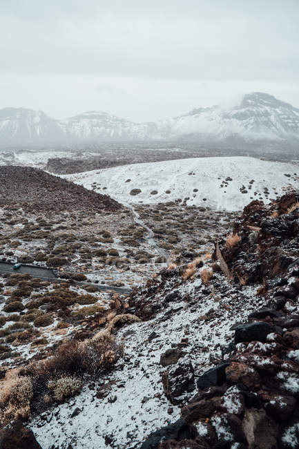 Grasbewachsenes Tal mit Schnee bedeckt, Bergkette im Hintergrund — Stockfoto