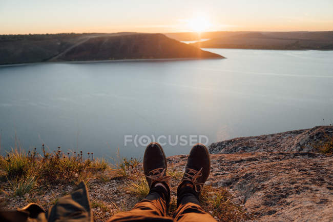 Crop legs of tourist resting at coast of wide river — Stock Photo