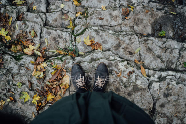 Gambe femminili in piedi su scale rocciose con foglie autunnali — Foto stock