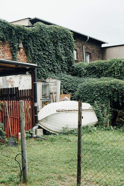 Вид на двор со сложенными окнами и лодкой над плющом — стоковое фото