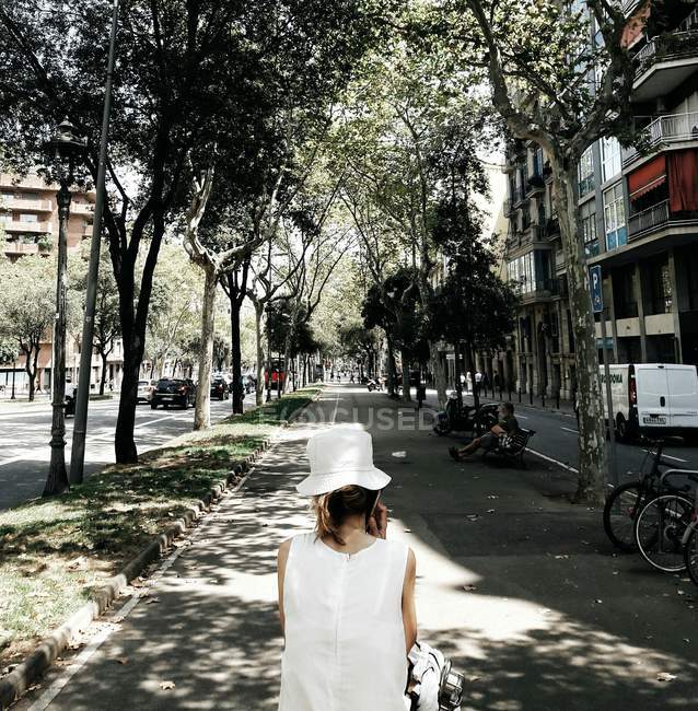 Вид сзади на девушку в белой панамской шляпе на летней улице — стоковое фото