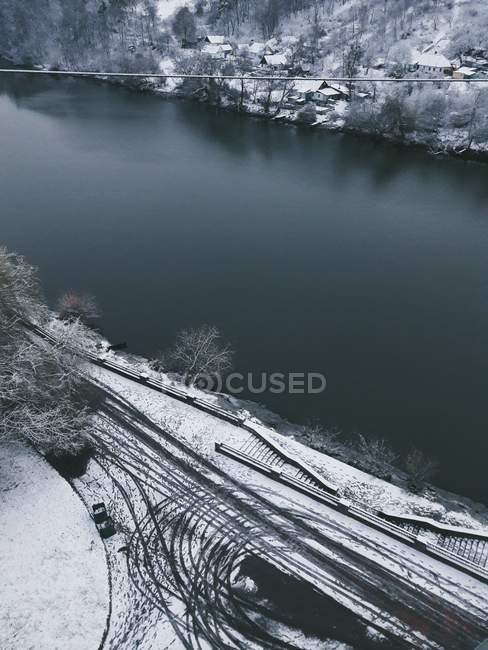 Vue en angle élevé sur la rive de la rivière d'hiver avec des pistes de roue — Photo de stock