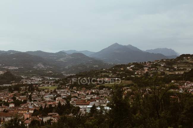 Idyllic landscape with town in valley over misty hills on cloudy day — Stock Photo
