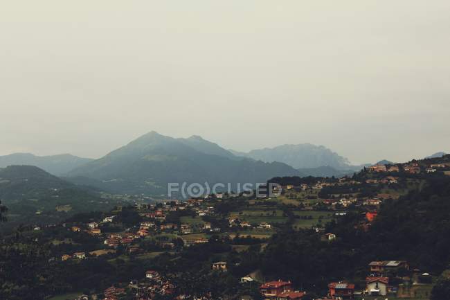 Vista idílica para a cidade no vale sobre colinas nebulosas no dia nublado — Fotografia de Stock