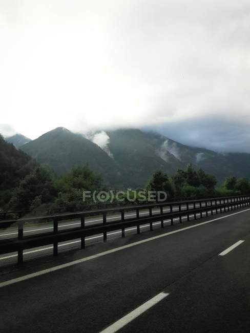 Estrada de asfalto correndo ao longo do terreno nebuloso da montanha — Fotografia de Stock