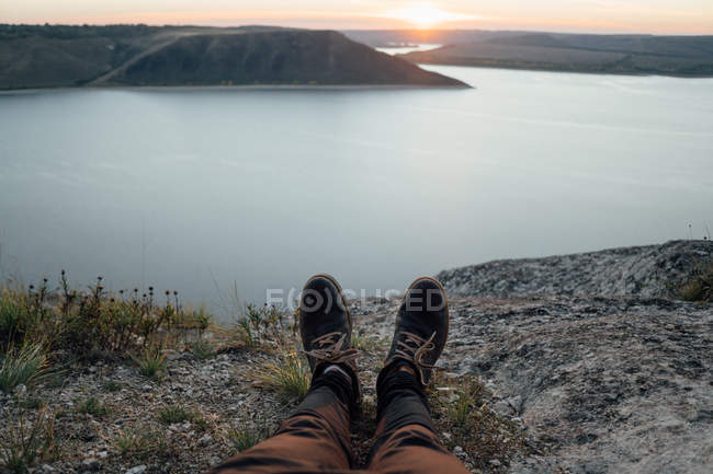Ноги туриста, отдыхающего на берегу широкой реки — стоковое фото