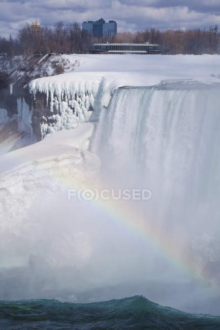 Arcobaleno sulla cascata del Niagara con edifici della città sullo sfondo, Ontario, Canada — Foto stock