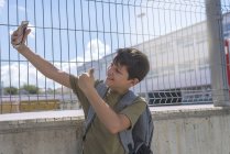 Студент делает селфи и показывает большой палец перед камерой на улице — стоковое фото