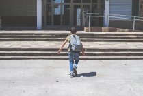 Вид сзади на школьника, бегущего в здании школы — стоковое фото