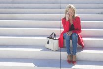Donna seduta sulle scale e parlare su smartphone — Foto stock