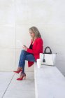 Женщина сидит на лестнице и использует цифровой планшет на открытом воздухе — стоковое фото
