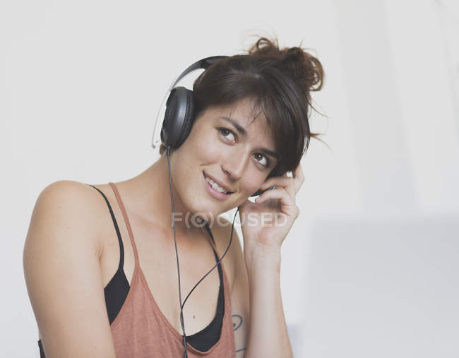 Mujer joven usando auriculares mirando hacia otro lado - foto de stock