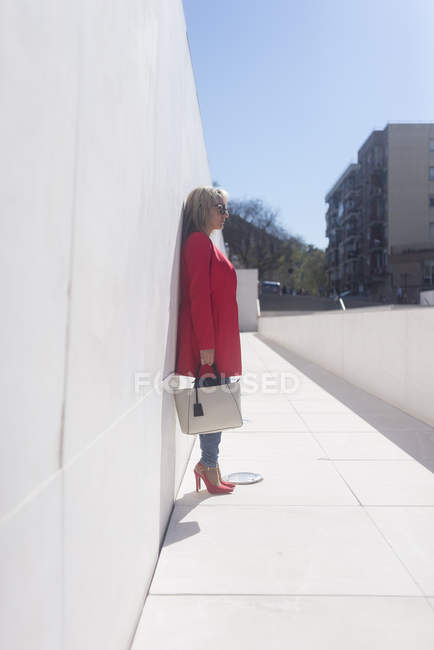 Стильний середині дорослої жінки, спираючись на стіні на відкритому повітрі — стокове фото