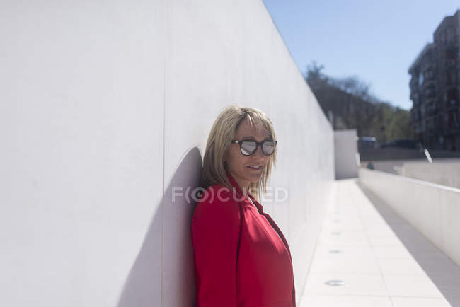 Stilvolle erwachsene Frau, die sich im Freien an die Wand lehnt — Stockfoto