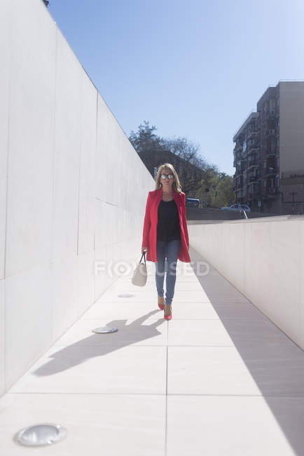 Woman in sunglasses walking at urban city street — Stock Photo