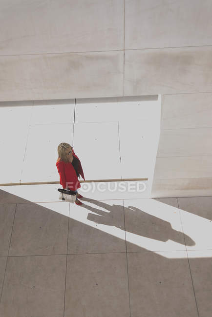 Blick von oben auf eine Frau im roten Mantel, die in der Stadt spaziert — Stockfoto